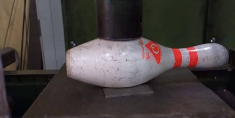 Une boule et une quille de bowling écrasées avec une presse hydraulique Presse hydraulique sur une boule et une quille de bowling
