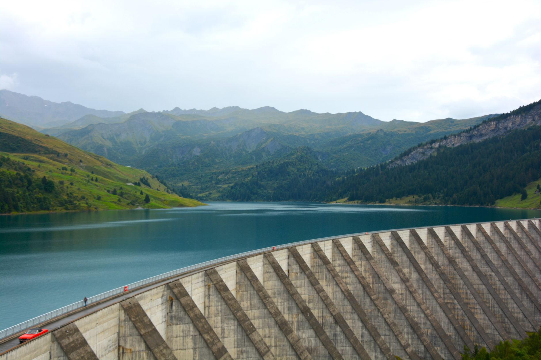 Un paysage de montagne pittoresque avec un grand barrage et le reflet d'un lac serein.