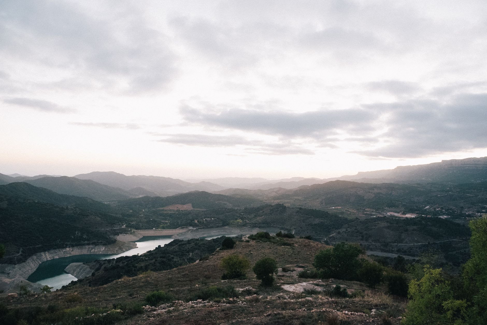 Superbe paysage du réservoir de Siurana en Espagne avec des collines brumeuses et des ciels nuageux.