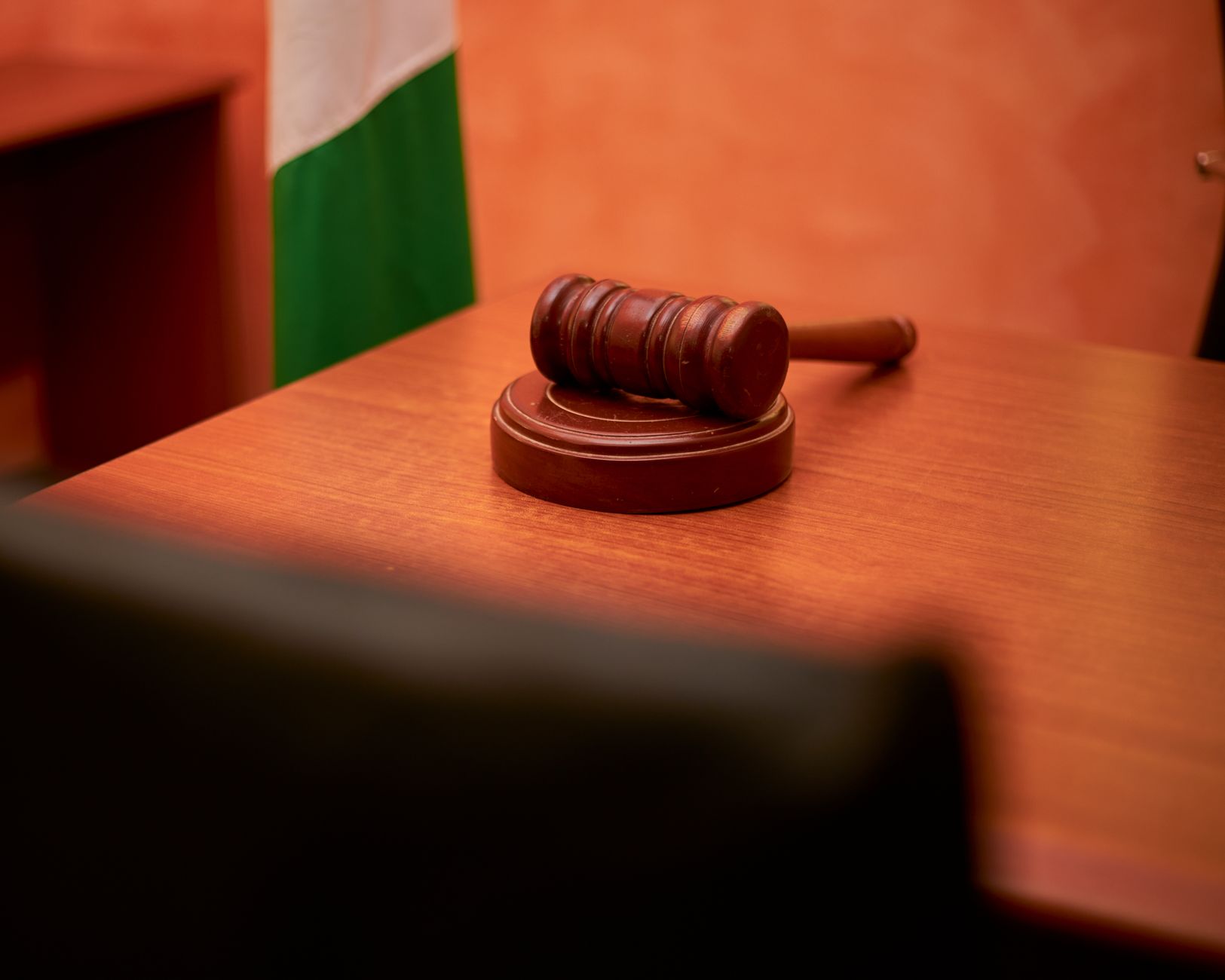 Un marteau de juge posé sur un bureau de tribunal en bois.